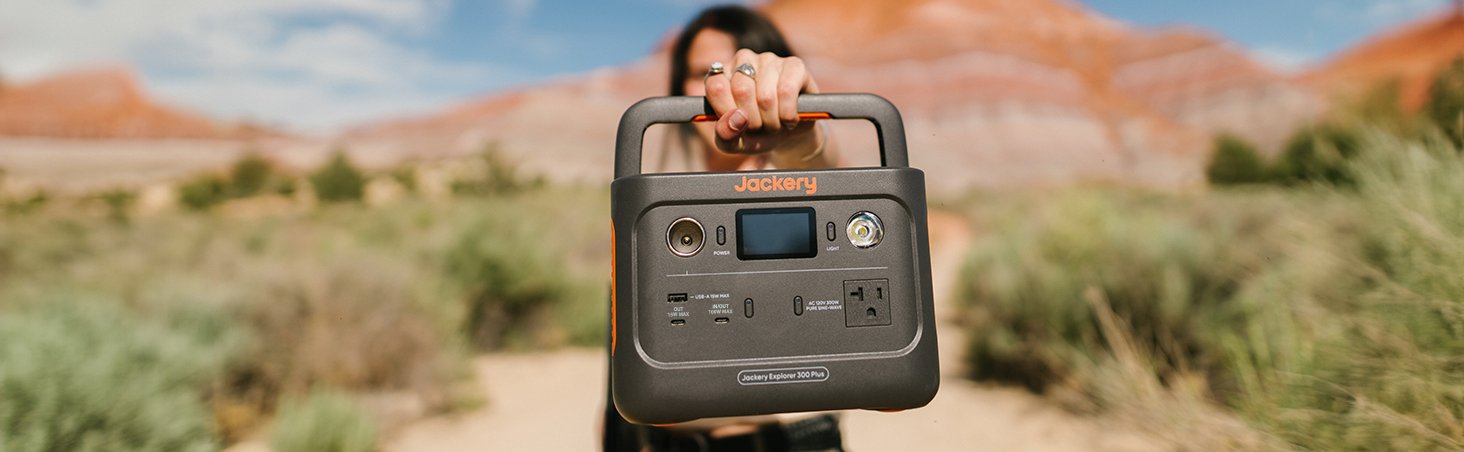 Jackery Explorer 300 Plus portable power station held outdoors in desert landscape